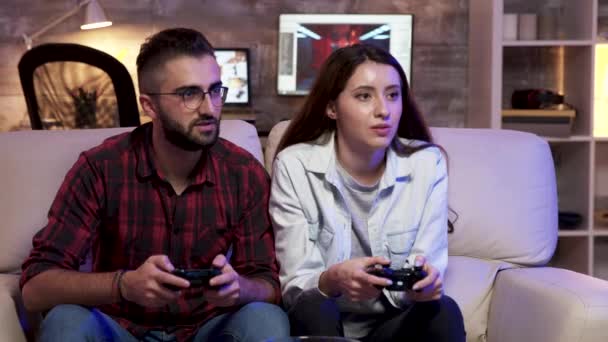 Ζευγάρι κάθεται στον καναπέ χαλαρώνοντας παίζοντας βιντεοπαιχνίδια - Πλάνα, βίντεο