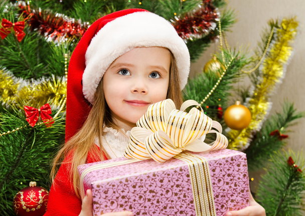 little girl in santa hat with present have a christmas - Fotó, kép