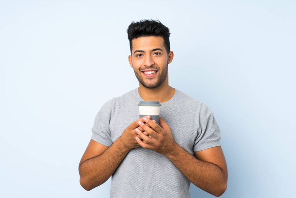 Young handsome man over isolated background holding coffee to take away - Photo, Image