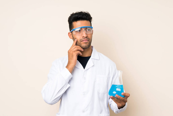 Young handsome man over isolated background with a scientific test tube - Photo, Image