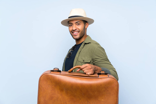 Giovane bell'uomo che tiene una valigetta vintage su uno sfondo blu isolato
 - Foto, immagini
