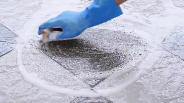 Hand of man met blauwe rubberen handschoenen wordt gebruikt om scrub reiniging om te zetten op de tegelvloer. - Video