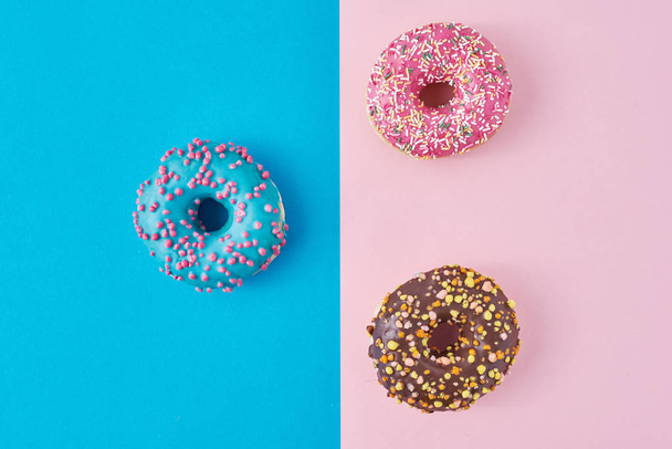 Pastel pembe ve mavi arka planda donutlar. Minimalizm yaratıcı yemek kompozisyonu. Düzleştirme biçimi - Fotoğraf, Görsel