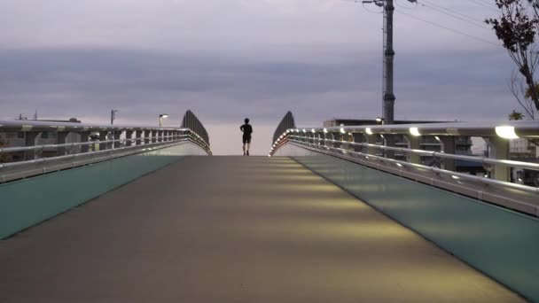 Een man die wegloopt over een lege brug. - Video
