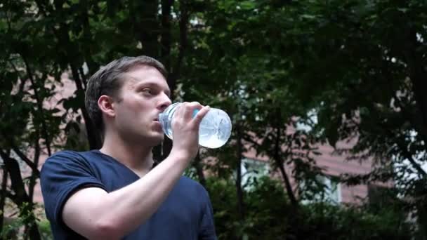 ein Mann trinkt aus einer durchsichtigen Plastikflasche - Filmmaterial, Video