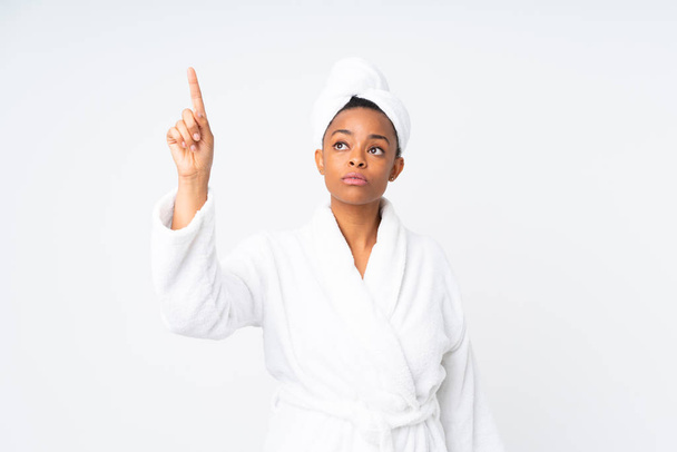 Afrikkalainen amerikkalainen nainen kylpytakissa yli eristetty tausta koskettaa läpinäkyvällä näytöllä
 - Valokuva, kuva