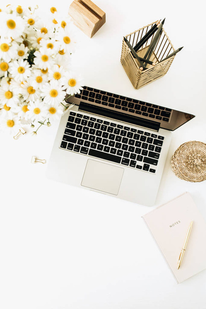 Home office desk workspace with laptop, chamomile daisy flowers bouquet and notebook on white background. Flat lay, top view minimal hero header with copy space mockup. - Photo, Image