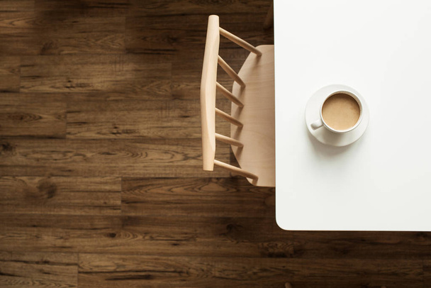 Kopje koffie met melk op witte tafel bij designstoel en houten vloer. Top view modern interieur meubelconcept. - Foto, afbeelding
