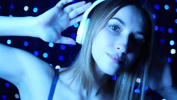 portrait of a girl in headphones in neon light on a background garlands - Photo, Image