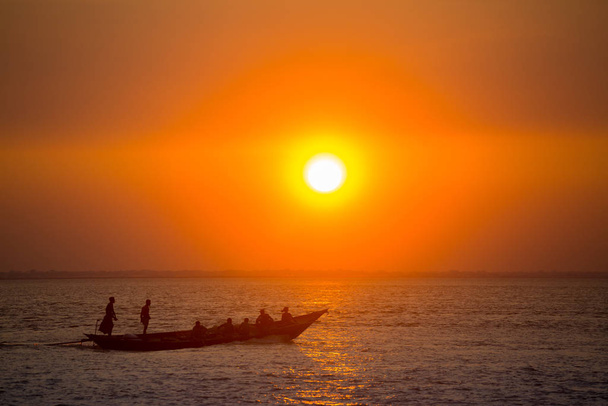 Colorido atardecer dorado en el mar. Los Fishermans están regresando a casa con peces, manualmente al atardecer en la playa de Char Samarj en Chandpur, Bangladesh
. - Foto, imagen