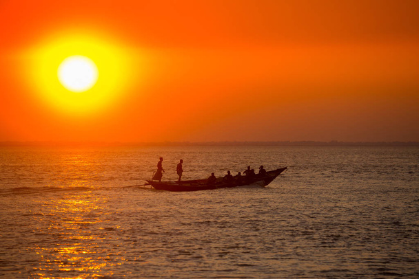 Colorido atardecer dorado en el mar. Los Fishermans están regresando a casa con peces, manualmente al atardecer en la playa de Char Samarj en Chandpur, Bangladesh
. - Foto, Imagen
