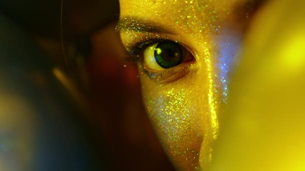 Лицо девушки крупным планом с золотыми блестками среди золотых воздушных шаров
 - Кадры, видео