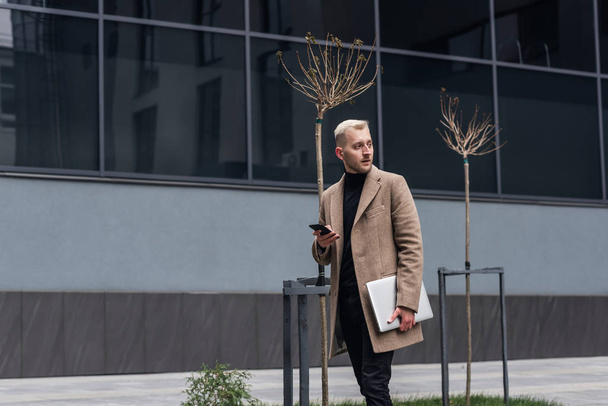 Businessman with laptop walking on the city street. - Foto, Imagem