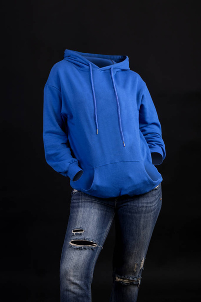 Üres ruhák láthatatlan szexi nő visel kék kapucnis pulcsi és szűk farmer pózol elöl nézet - Fotó, kép