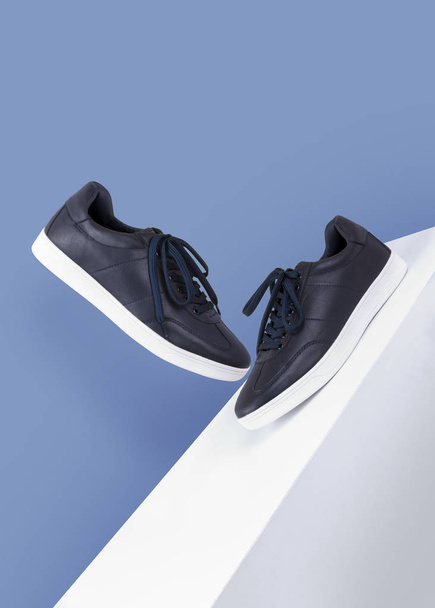 dark blue sneakers shoes floating on a white box on a blue background side and front view product mood shot - Photo, Image