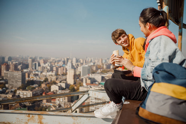 Happy boyfriend looking at girlfriend having lunch on roof - Fotografie, Obrázek
