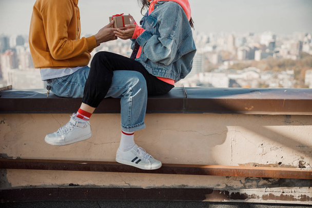 Girl sitting near her boyfriend on rooftop - Zdjęcie, obraz