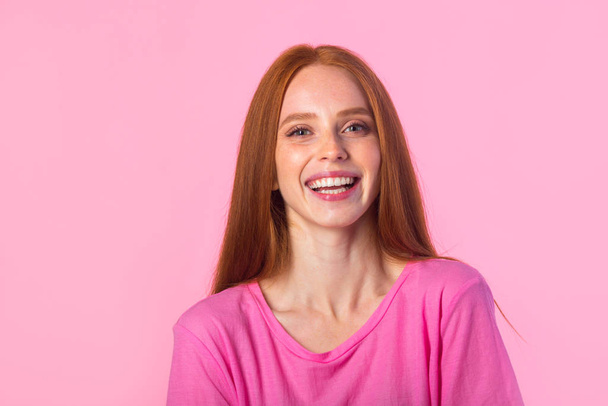 beautiful young woman with red hair on a pink background - 写真・画像