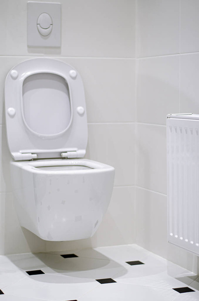 Interior. A white toilet bowl hangs on a white tile wall in a white bathroom - Photo, Image