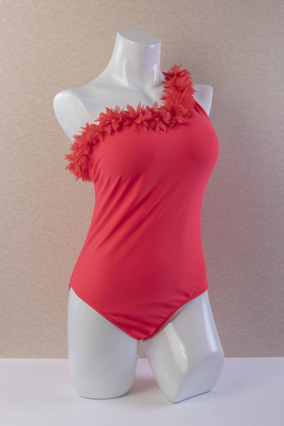 schöne One-Shoulder Top einteilig trendiger roter sexy Badeanzug auf Schaufensterpuppe auf strukturiertem Hintergrund Vorderansicht - Foto, Bild