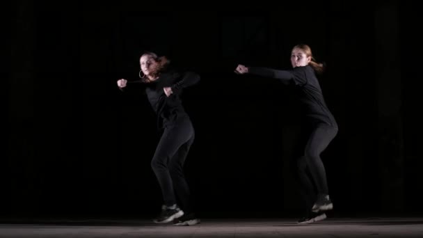 dúo de mujeres jóvenes hermosas bailando hip hop, baile callejero sobre un fondo negro en el estudio, aislado
 - Imágenes, Vídeo