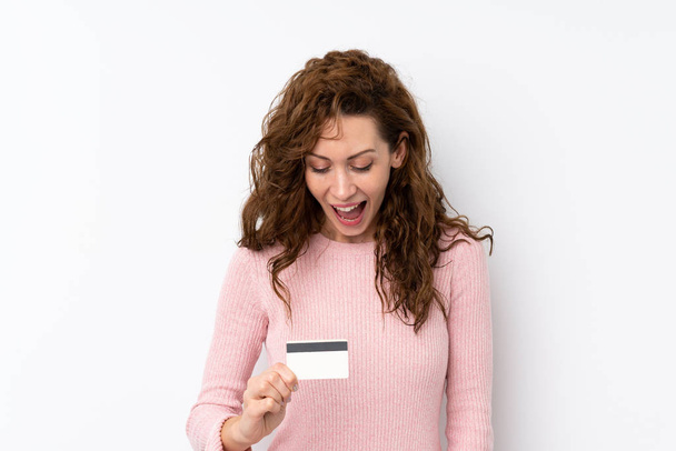 Νεαρή όμορφη γυναίκα πάνω από απομονωμένο υπόβαθρο κρατώντας μια πιστωτική κάρτα - Φωτογραφία, εικόνα