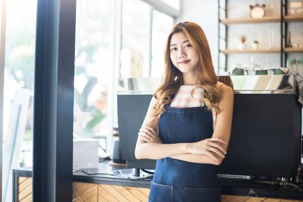 Pretty young asian waitress standing arms crossed in cafeteria.C - Photo, Image