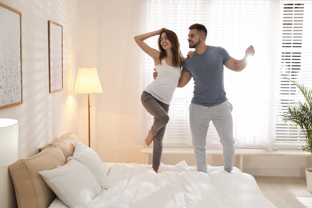 Lovely young couple dancing on bed at home - Φωτογραφία, εικόνα