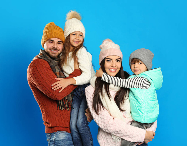 Happy family in warm clothes on blue background. Winter vacation - Zdjęcie, obraz