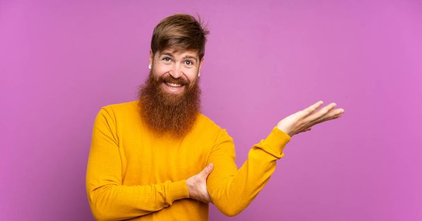 Рудий чоловік з довгою бородою над ізольованим фіолетовим тлом, що розтягує руки на бік, щоб запросити прийти
 - Фото, зображення