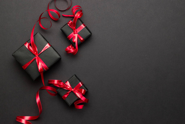 Ajándékdoboz szalag. Karácsonyi ajándékok, piros dekoráció fekete háttérrel. Karácsonyi ajándék. Téli ünnep koncepció. Újév. Noel. - Fotó, kép