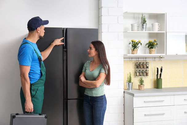 Technicien masculin parlant avec le client près du réfrigérateur dans la cuisine
 - Photo, image