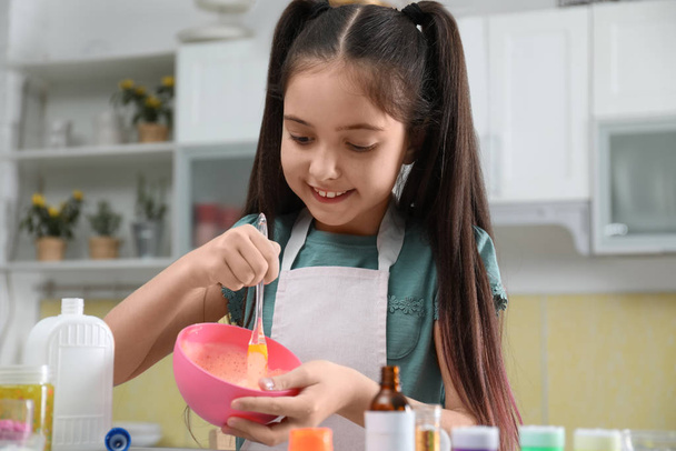 Cute little girl mixing ingredients with silicone spatula at tab - Фото, зображення