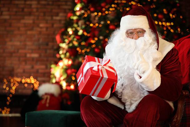 Santa Claus with gift box near Christmas tree indoors - Foto, Imagem