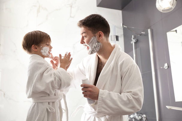 Dad applying shaving foam onto son's face in bathroom - Zdjęcie, obraz