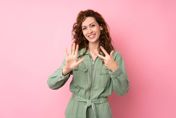 Молода красива жінка над ізольованим рожевим тлом підраховує вісім з пальцями
 - Фото, зображення