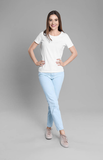 Young woman in stylish jeans on grey background - Zdjęcie, obraz