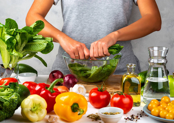 A nő zöldsalátát készít, salátát főz egy üvegtálban a konyhában. Egészséges táplálkozás koncepciója. - Fotó, kép
