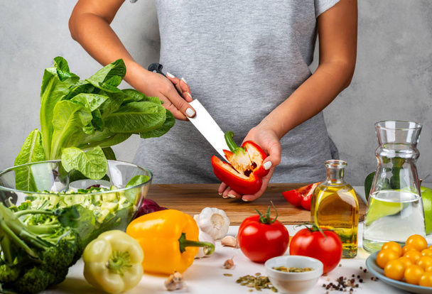A mulher limpa pimentas, cozinha salada na cozinha. Conceito de dieta saudável
. - Foto, Imagem