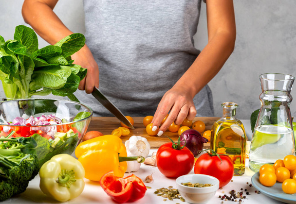 Mulher corta tomates cereja amarelos e salada de cozinha na cozinha. Conceito de dieta saudável
. - Foto, Imagem