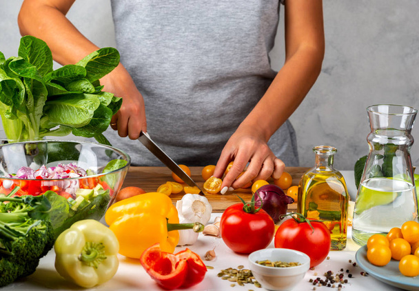 Mulher corta tomates cereja amarelos e salada de cozinha na cozinha. Conceito de dieta saudável
. - Foto, Imagem