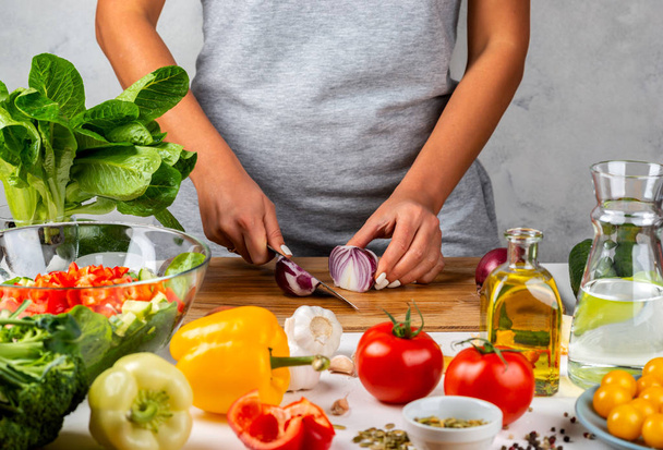 Kadın soğan doğruyor ve mutfakta salata yapıyor. Sağlıklı diyet kavramı. - Fotoğraf, Görsel
