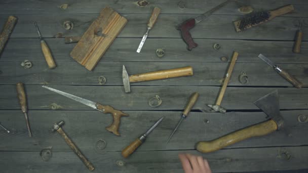 Old hand tools. Top view. Slow motion. The male hand takes the hammer from the table and after a while puts it back.On the table are mixed work tools (screwdrivers, chisels, hand saw, hammers, ax, awl, metal brush, jointer) of the 60s, 70s, 80s. - Footage, Video