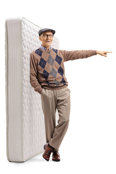 Senior gentleman leaning on a bed mattress and pointing to one s - Foto, Imagem