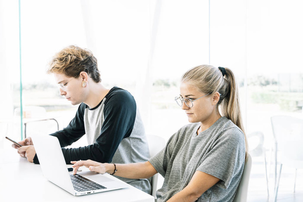 Nő és fiatal férfi dolgozik egymás mellett egy íróasztalnál egy munkaterület - Fotó, kép