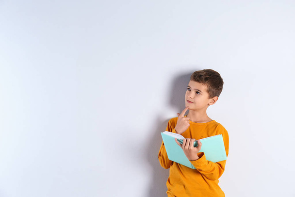 Cute little boy with book on light background, space for text - Foto, immagini