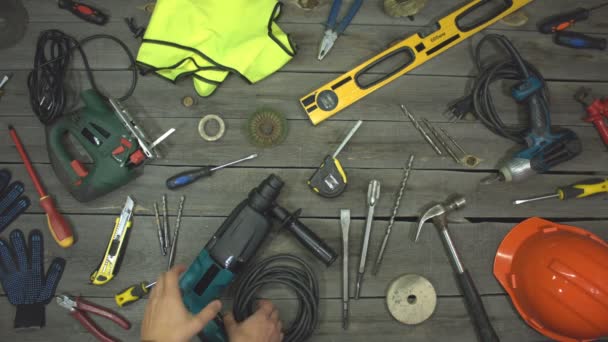 A variety of electro and hand tools and special clothing. Top view. Slow motion.The male hand takes the rotary hammer from the table and after a while puts it back. - Footage, Video