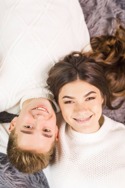 Young beautiful couple lies on the floor in a beautiful white room and smiling - Photo, image