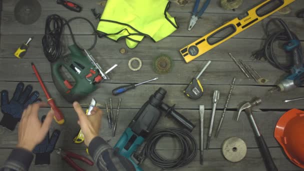 A variety of electro and hand tools and special clothing. Top view. Slow motion.The male hand takes an electric jigsaw from the table and after a while puts it back. - Footage, Video