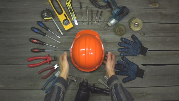 A variety of electro and hand tools, safety helmet and gloves. Top view. Slow motion.The male hand takes a helmet from the table and after a while puts it back. - Footage, Video